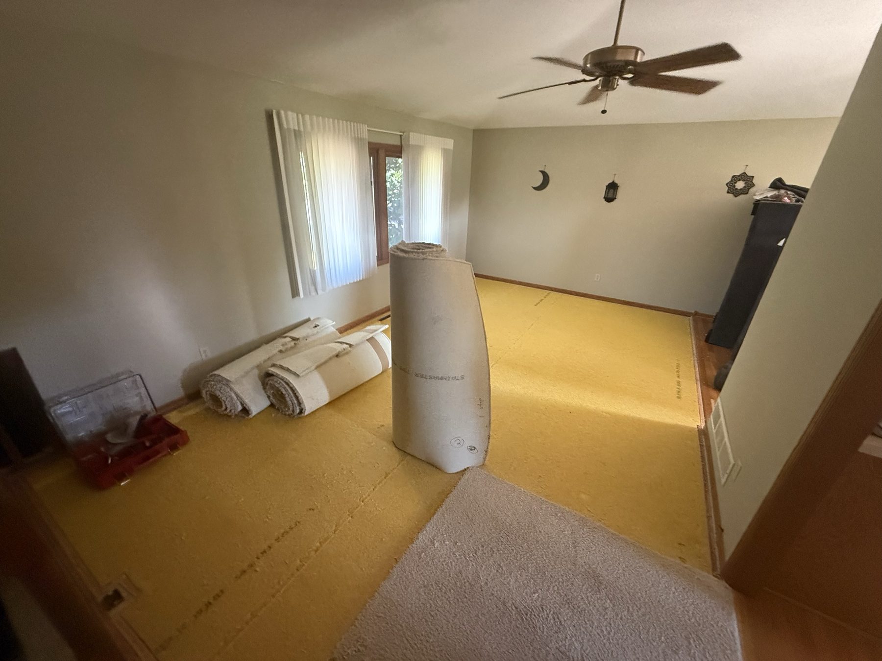 The living room before, with old carpet and exposed yellow pad
